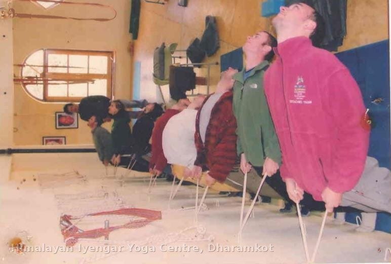 A group class practising a supported backbend using stools